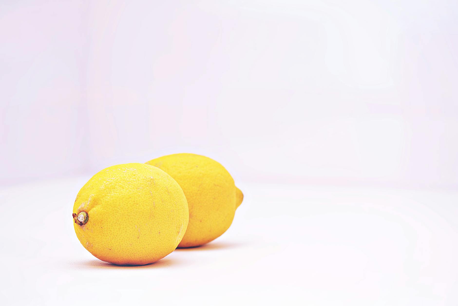 Bright yellow lemons against a minimalistic white background, symbolizing fresh, joyful sensations