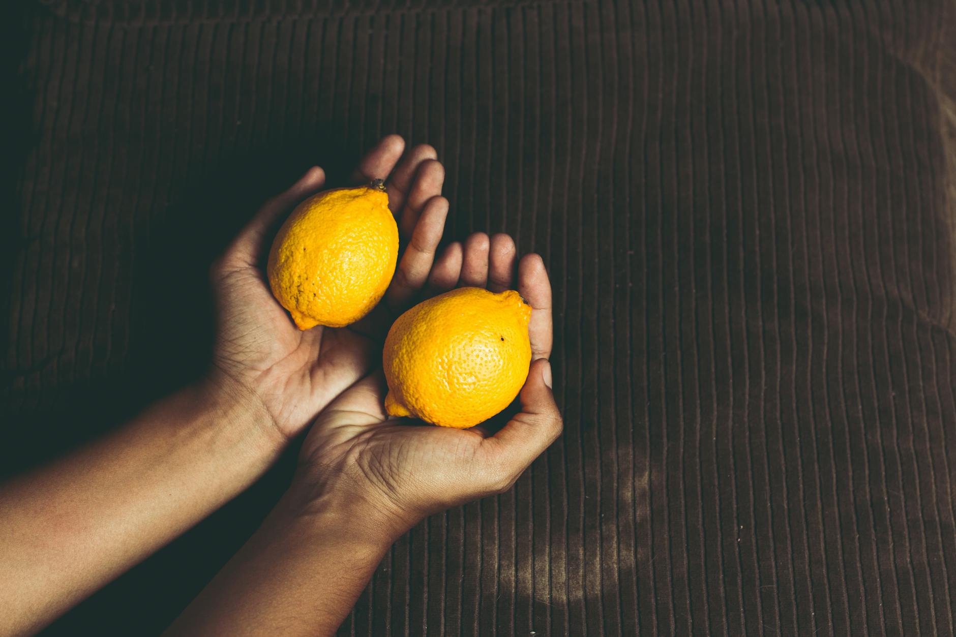 Two fresh lemons held in cupped hands, symbolizing gentle care and natural comfort