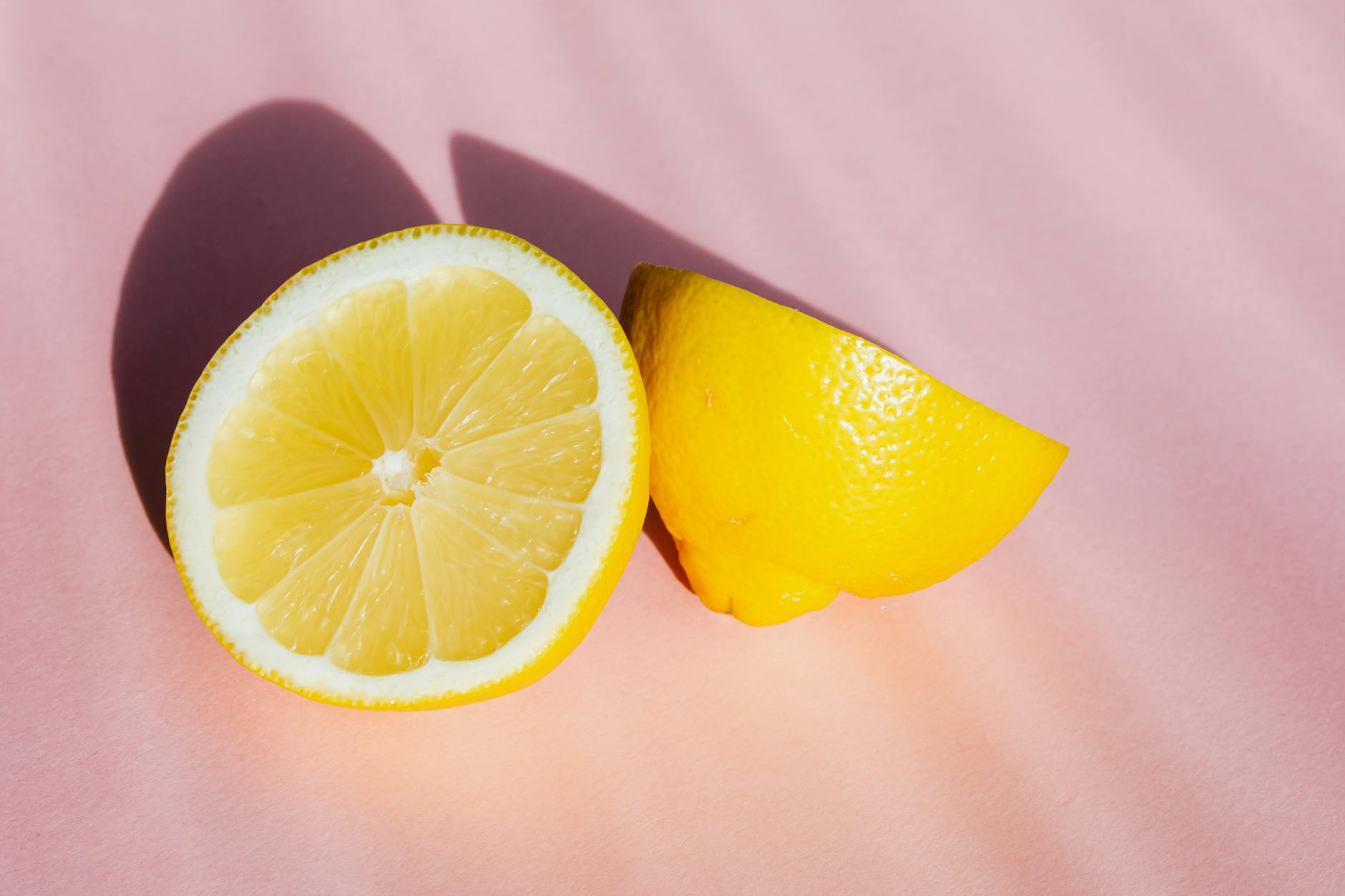 Moitiés de citron frais sur fond rose dans la lumière du soleil