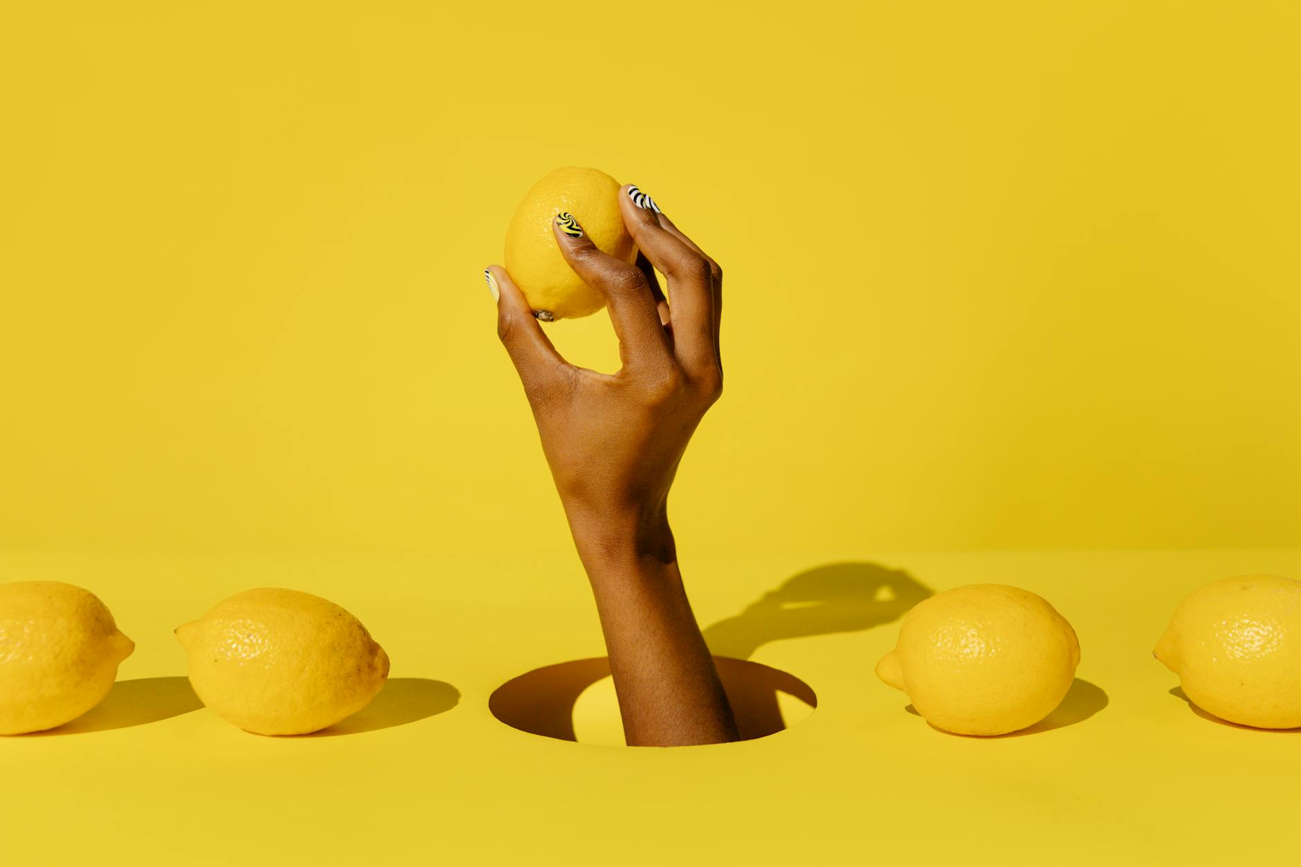 Citrons jaunes vifs arrangés sur un fond vert pastel, représentant la fraîcheur et la sensibilité délicate
