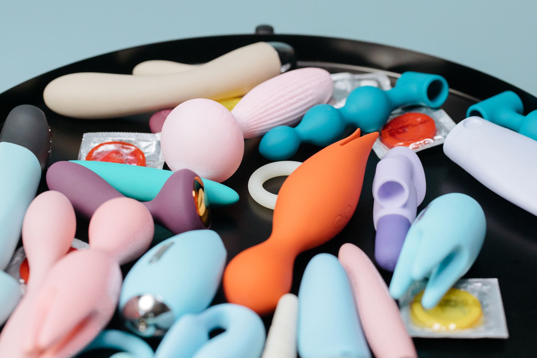 A collection of various sex toys on a black tray, showcasing diverse designs and textures