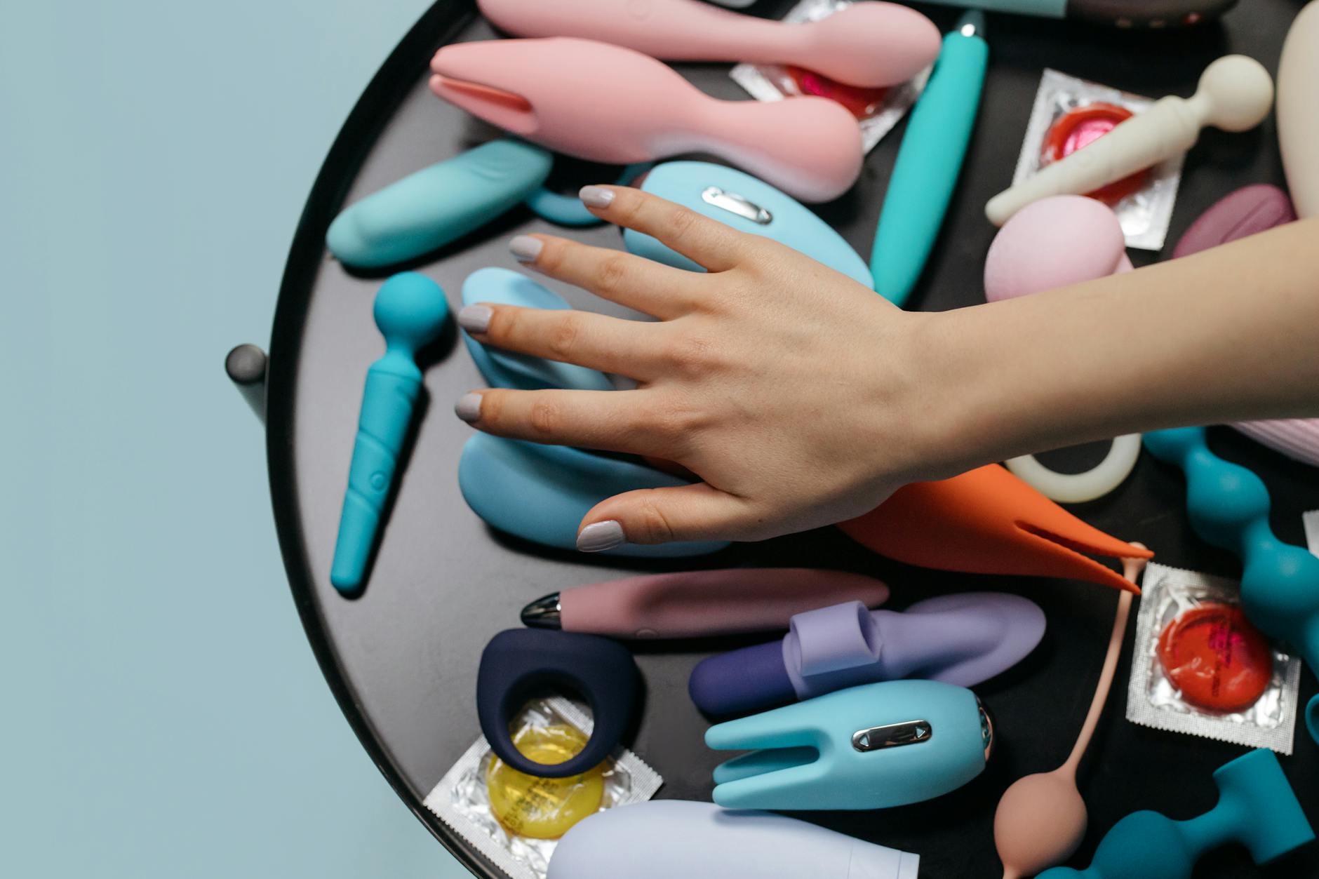 A woman holding two colorful clitoral vibrators, representing diverse intimate wellness options