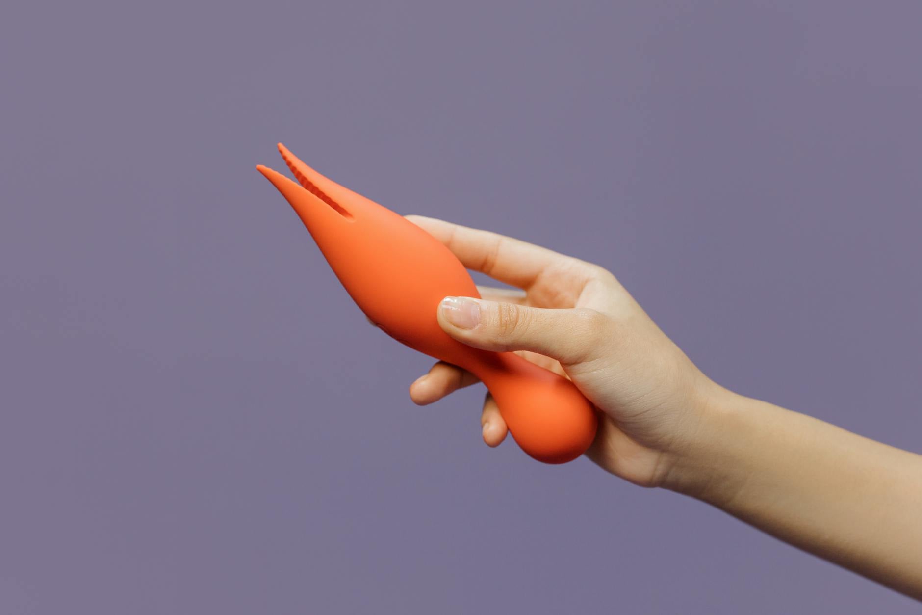 A hand holding a lemon-shaped vibrator against a purple backdrop, symbolizing intimate connection across distance
