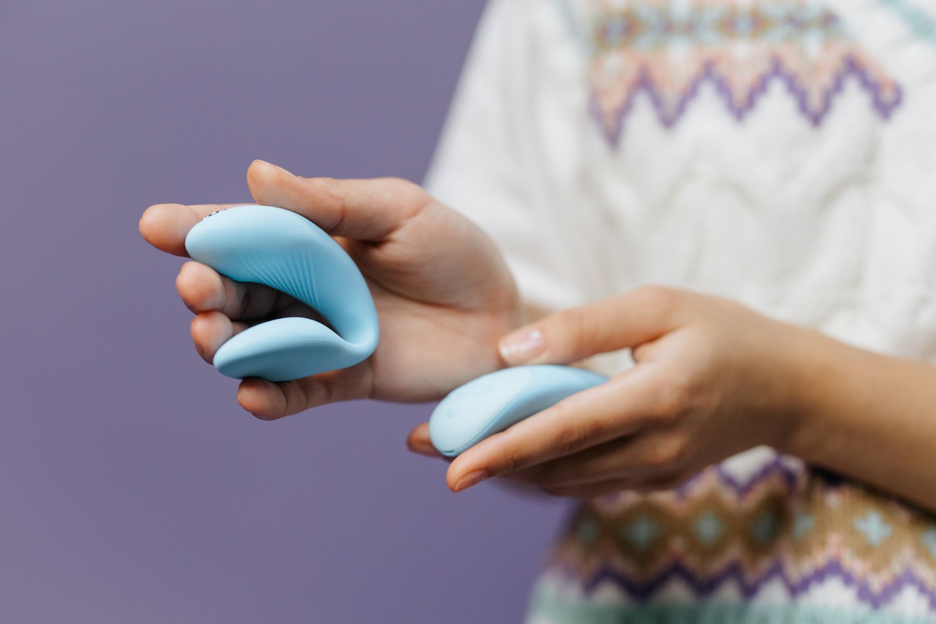 Close-up of hands holding a sleek blue vibrator against a purple background, symbolizing rediscovering pleasure.