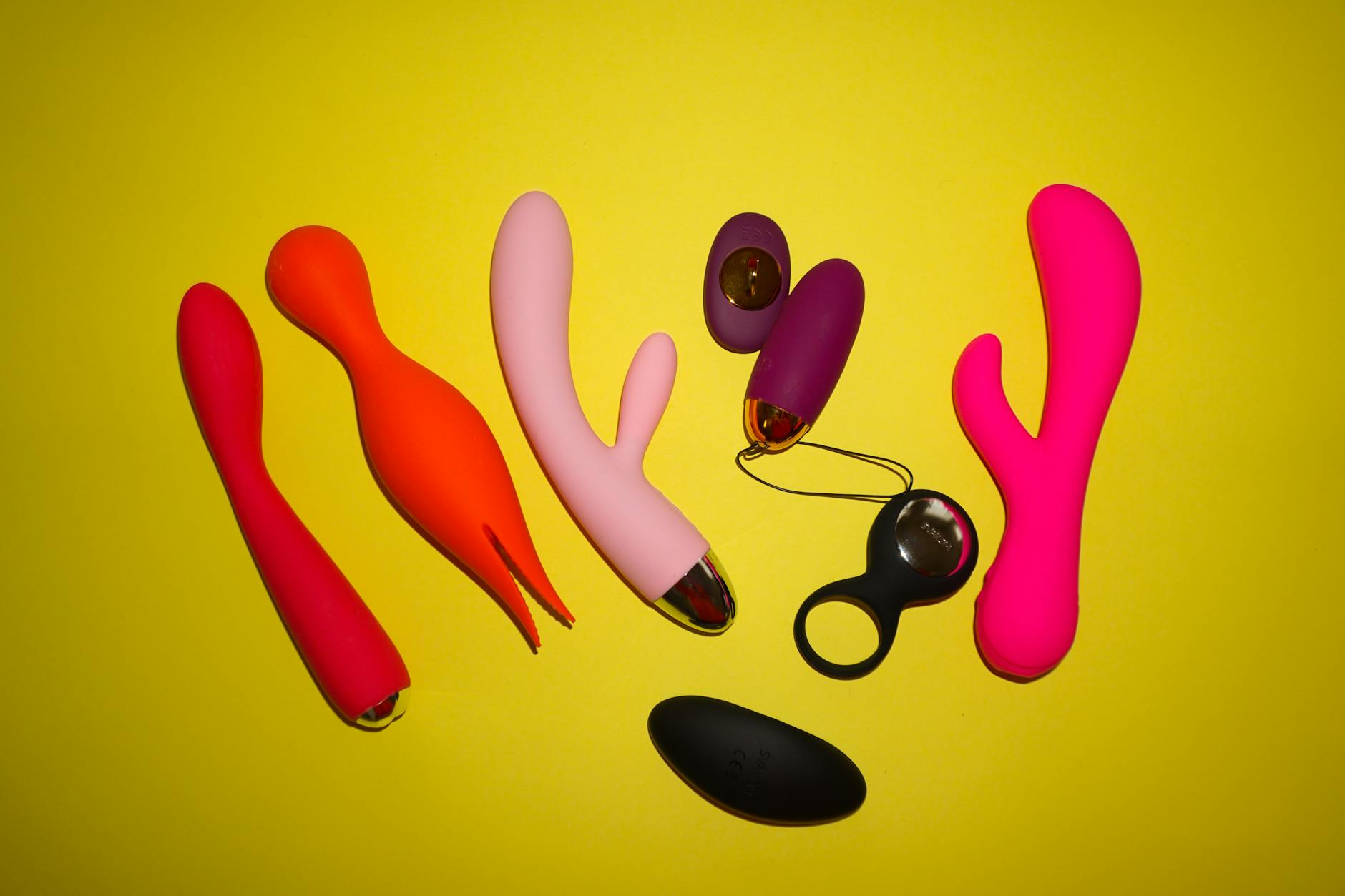 A blue vibrator surrounded by flowers and citrus slices on a bright yellow background, symbolizing playful self-discovery